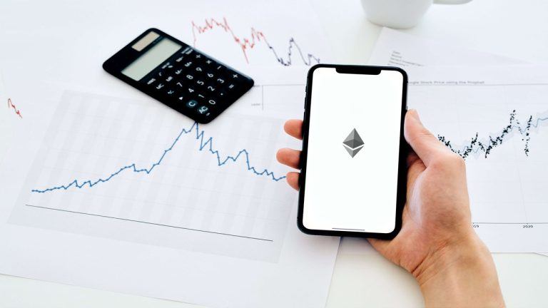 Image of a man holding a smartphone with Ethereum's logo on it.