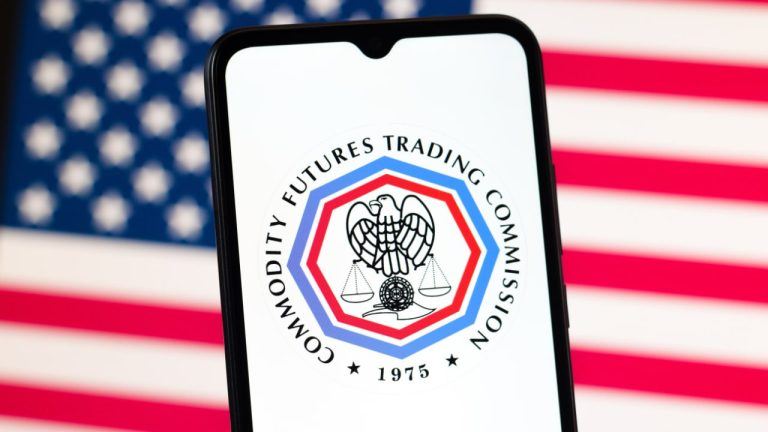CFTC logo on a phone screen ahead of a US flag in the background
